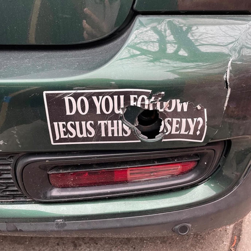 DO YOU FOLLOW JESUS THIS CLOSELY? A bumper sticker on a dented, rear-ended car, with a hole punched right through the middle of it.