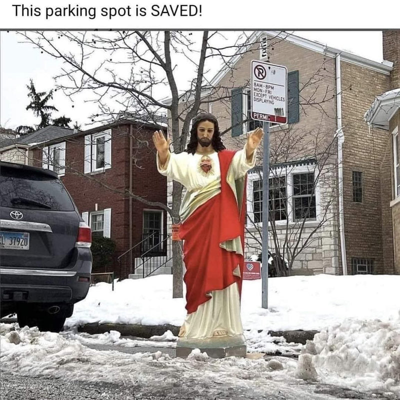 This parking spot is SAVED! A Sacred Heart Jesus statue with arms raised stands in a cleared snowy parking space on a city street.