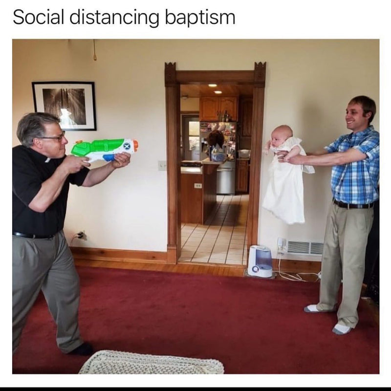 Social distancing baptism. A priest aims a Super Soaker water gun at a baby in a white christening gown held out at arm's length across the room.