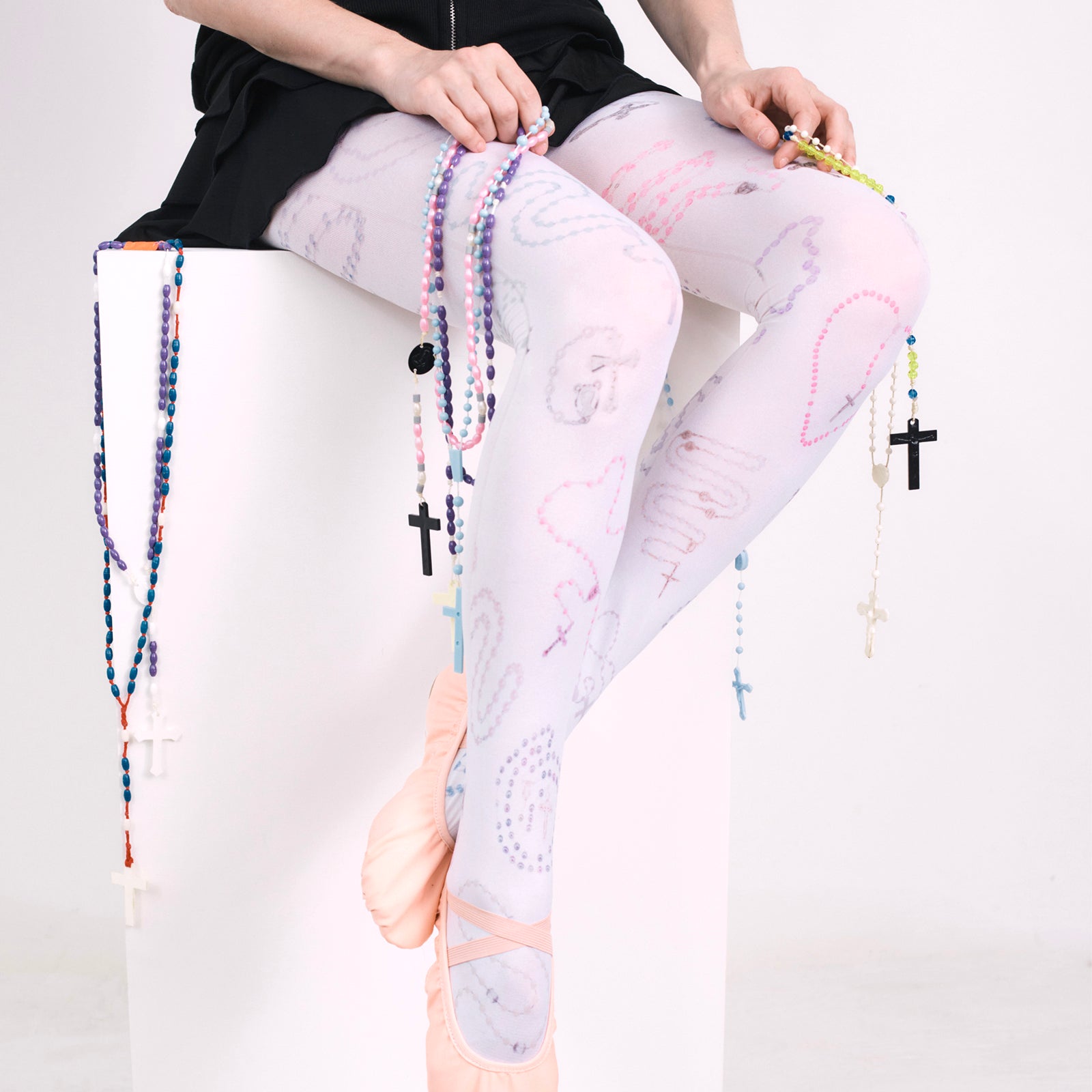 Model wearing all-over print rosary tights with rosary accessories. 
